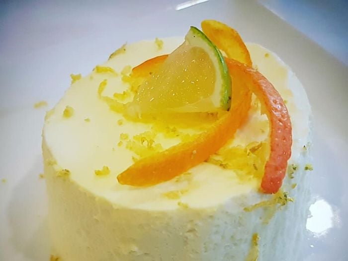 Eit bilete av ein dessert på ein talleren, ein fromasj med sitrusskall på toppen.