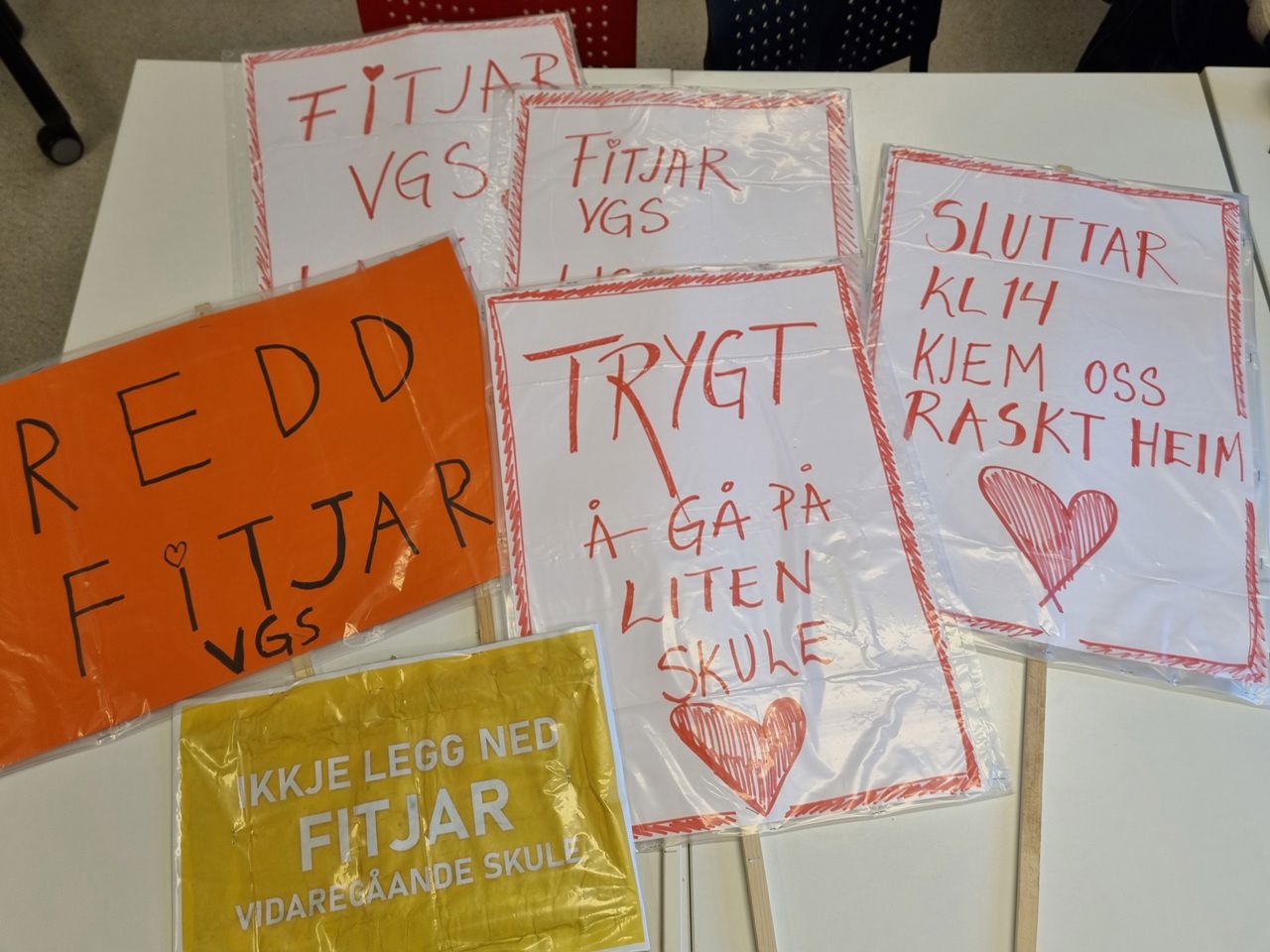 Mange plakatar som ligg på eit bord, med tekst som "redd fitjar vgs", "trygt å gå på liten skule" osb.